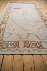 Angled view of distressed Oushak runner, showing faded abrashed ivory field and copper designs.