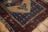 Vintage Hamadan rug corner detail: deep madder root border, indigo field, exposed foundation, and tattered fringe.