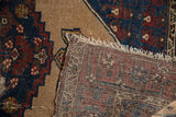 Close-up: vintage Hamadan rug pile with visible wear, tattered fringe, and hand-knotted foundation.