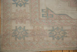 Distressed vintage Oushak rug corner with pale denim, dusty pink geometric border details.