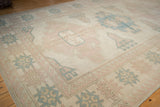 Distressed vintage Oushak rug corner, geometric floral buds, dusty pink and pale denim blue.