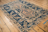 Distressed vintage Melas rug showing geometric cobalt blue border and beige interior field.