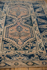 Distressed geometric patterns in beige and cobalt blue with visible wear on a vintage Melas rug.