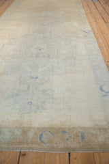Distressed vintage Oushak runner, showing faded dusty denim blue motifs on short ivory pile.
