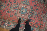 Distressed Melas carpet with central pomegranate medallion, geometric pattern, and muted brick red, sky blue.