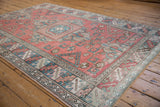 Distressed vintage Melas carpet in dusty red, sky blue, and pale rose geometric design.
