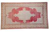 Vintage distressed Oushak carpet with faded pale cherry red medallion, ivory field, and scrolling spandrels.