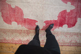 Distressed Oushak rug pile with fading cherry red and ivory scrolling patterns.