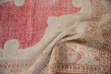 Distressed vintage Oushak carpet showing worn cherry red pattern on beige with exposed knot heads.