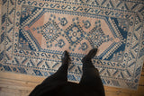 Distressed vintage Melas rug: abrashed peach field with navy geometric patterns and borders.