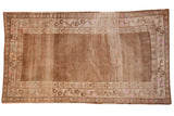 Distressed vintage Kars carpet featuring allover seed pattern and faded brown, beige, and pink borders.