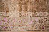 Distressed Kars carpet border featuring pink floral buds and geometric seed field pattern.