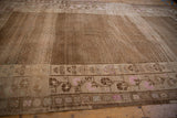Brown and pink floral border and distressed seed pattern of vintage Kars carpet.