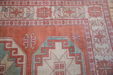 Distressed Oushak rug corner: geometric floral border and gul in cinnabar, ivory, sky blue.
