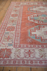 Distressed vintage Oushak rug's pale cinnabar red field and repeating geometric floral border.