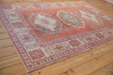 Distressed Oushak rug corner showing geometric floral border with soft cinnabar, ivory, blue.