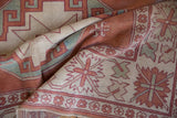 Textured pile of distressed Oushak rug, featuring cinnabar red and ivory geometric floral blossoms.