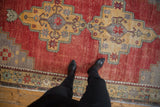 Distressed Oushak rug with even wear, featuring cherry red field and saffron geometric medallion.
