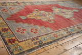 Distressed Oushak carpet with stepped geometric medallion and dusty cherry red field.