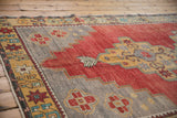 Distressed Oushak carpet shows gray and red stepped medallion with starburst motifs.
