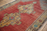 Distressed Oushak carpet with stepped medallion, starburst motifs, and dusty cherry red field texture.