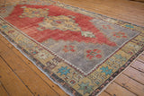 Colorful starburst and geometric floral border of vintage Oushak rug with faded red field.