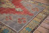 Detail of distressed Oushak rug's colorful starburst border and serrated floral finial.