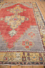 Distressed saffron yellow border with geometric starbursts on a vintage Oushak rug.