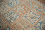 Angled detail of a distressed Turkish rug's repeating panels in pale terra cotta and denim blue.