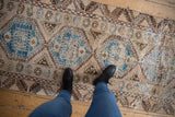 Distressed Oushak runner showing textured pile, sky blue medallions, and foundation wear.