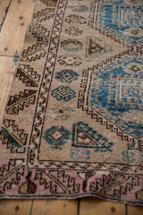 Distressed edge of vintage Oushak runner, showing worn pile, serrated border, and blue geometric motifs.