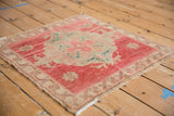 Distressed corner of a vintage Oushak rug with abrash, pale red border, and fringe.