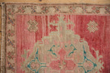 Distressed Oushak rug with abrashed pale red ground, beige, and turquoise floral motifs.