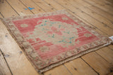 Distressed vintage Oushak rug showing even wear on pale red pile and beige floral border.