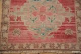 Distressed vintage Oushak detail with abrashed pale cochineal red, beige pile and floral motifs.