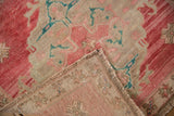 Distressed Oushak rug corner showing worn pale cochineal red pile, beige ground, and fringe.