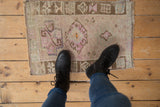 Vintage Kars rug mat on a wood floor, demonstrating its scale and distressed mauve pattern.