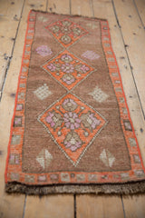 Distressed Kars rug side, vibrant tangerine orange selvage and geometric floral border.