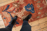 Distressed Oushak runner with expressive arts and crafts floral patterns in brick red and blue.
