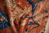 Crumpled detail of a vintage distressed Oushak rug, showing brick red and cobalt blue floral motifs.