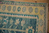 Distressed Oushak rug corner: pale saffron floral border, green zig-zag, ocean blue field.