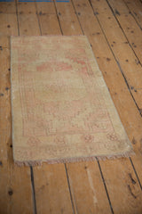 Distressed pile with pale gold and faded blush patterns on vintage Oushak rug mat.