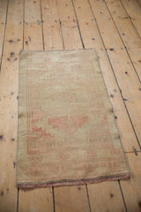 Bottom edge of distressed Oushak rug, showing pale gold fringe and faded blush pattern.