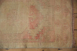 Distressed Oushak rug detail: worn pale gold pile, faint pattern, and dusty rose fringe.