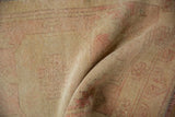 Muted pale gold and dusty rose distressed Oushak rug pile with even wear.