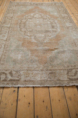 Close view of distressed Oushak rug, showing low pile and faded Rococo motif details.