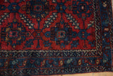 Ruby red field with serrated leaves and sapphire blue vine border on vintage Lilihan rug.