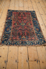 Lilihan rug corner: intricate indigo blue border, dusty red field, and end fringe.