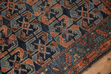 Close-up of antique Hamadan rug pile: cobalt blue field, dusty copper shrimp motifs, serrated border.