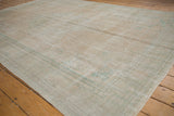 Distressed Oushak carpet, showing faded ivory and seafoam green texture.